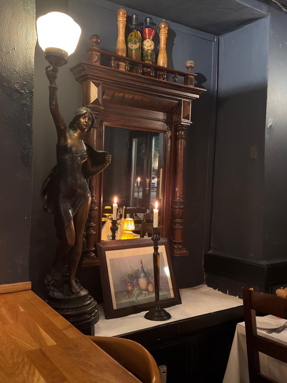 Foto fra Sale e Pepes galleri 13: Lodret nærbillede af statuelampen, træspejlet og levende lys